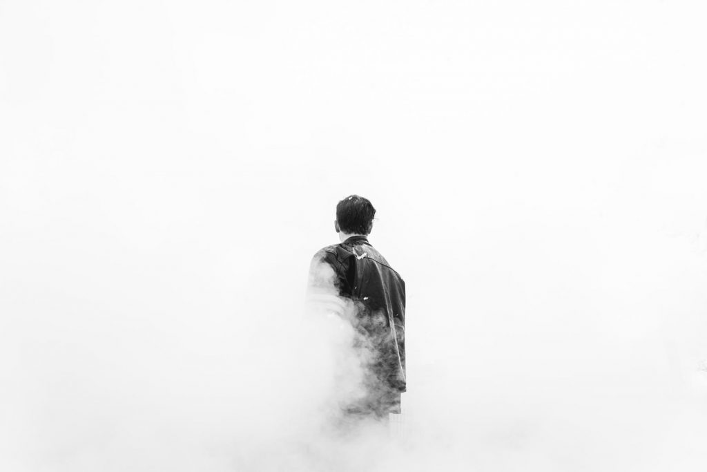 Adult with short hair walking away into fog